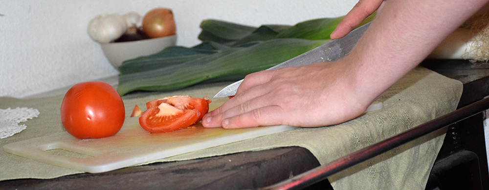 Bild på hand som skär tomater